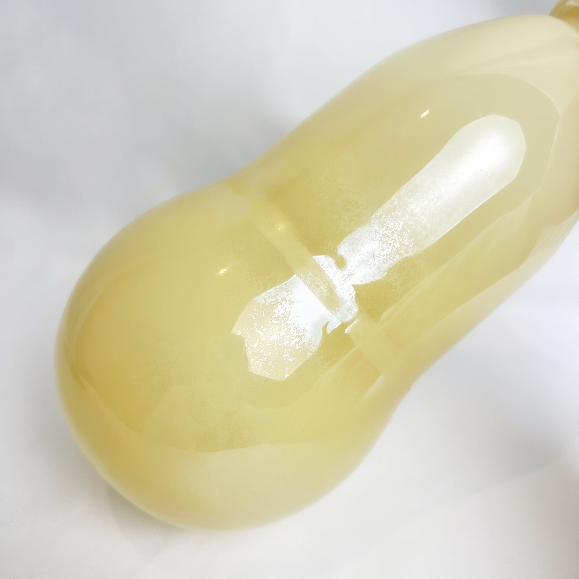 The light yellow gourd-shaped glass vase is showcased with a surface featuring numerous delicate speckles.