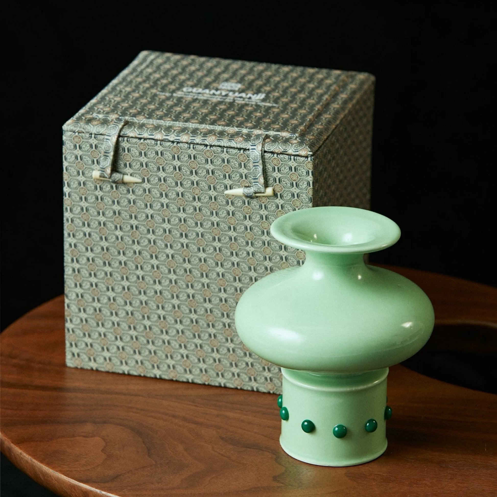 On a brown round table, there is a Chinese classical bamboo-shaped green vase inlaid with green jade, along with its packaging box.